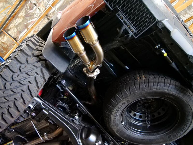 HKS Legamax Trail Master 2022 Tundra catback exhaust system installed on a pickup truck, showcasing the polished exhaust tips and piping.