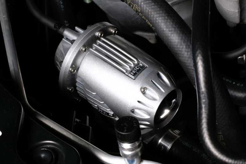 HKS Super SQV4 blow off valve installed on a vehicle, showcasing its black metal body and venting ports for turbocharged engines