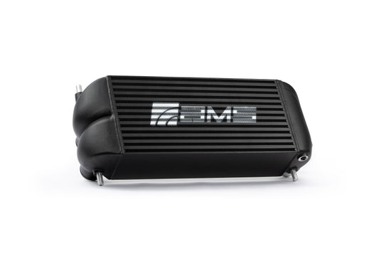 Black AMS Performance intercooler with logo for 2015+ Ford F-150 and Raptor 2.7L/3.5L EcoBoost engines, showing cooling fins and mounting points.