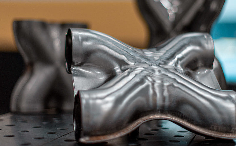 MagnaFlow Smooth Trans X 3/3 X 14 stainless steel X pipe for car exhaust systems, showing the polished metal and pipe connections.
