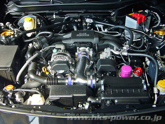 HKS Premium Cold Air Intake for ZN6/ZC6 FA20 engine, showing the sleek black intake pipe and filter in close-up view.