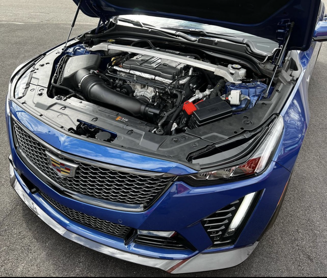 LMP Cadillac CT5-V Blackwing expansion tank showing a black plastic coolant reservoir with mounting brackets and hoses.