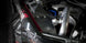 HKS Racing SQV universal blow off valve installed on a turbocharged engine, showcasing its sleek black design and metal components.